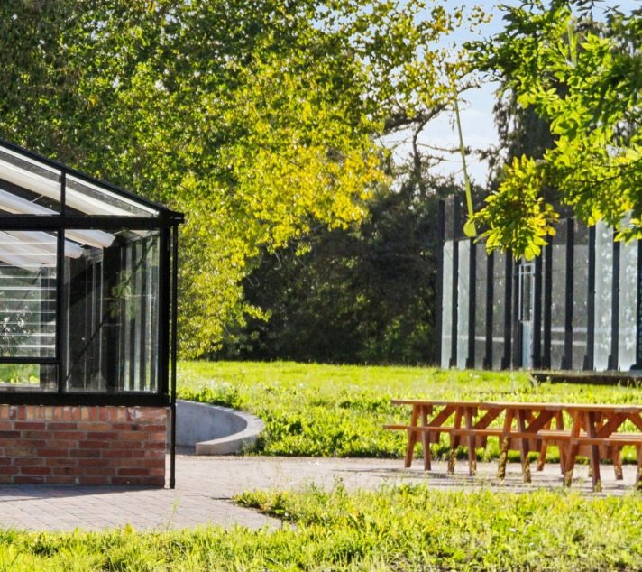 A care-home garden with a Nordic Garden Building among greenery and seating